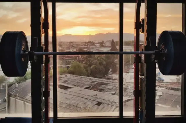 Loaded barbell in a power rack in front of a city view