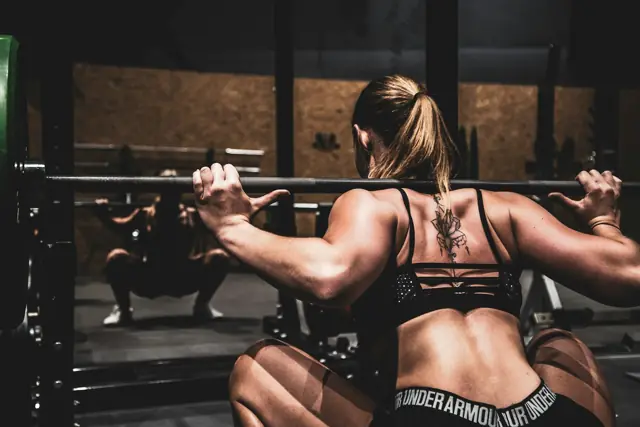 Woman performing a barbell back squat in a rack