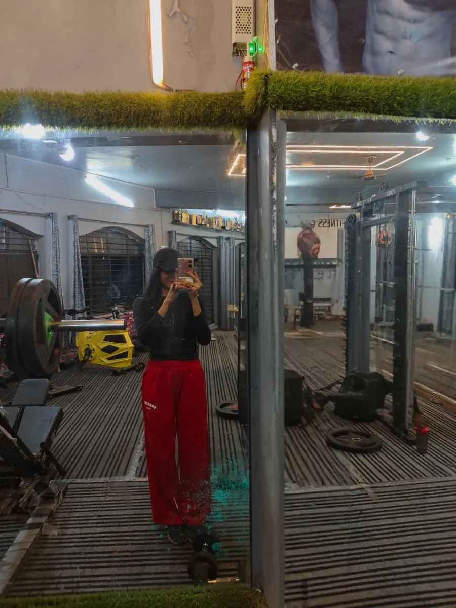 Khushi Gupta in the gym, mirror photo beside a loaded barbell