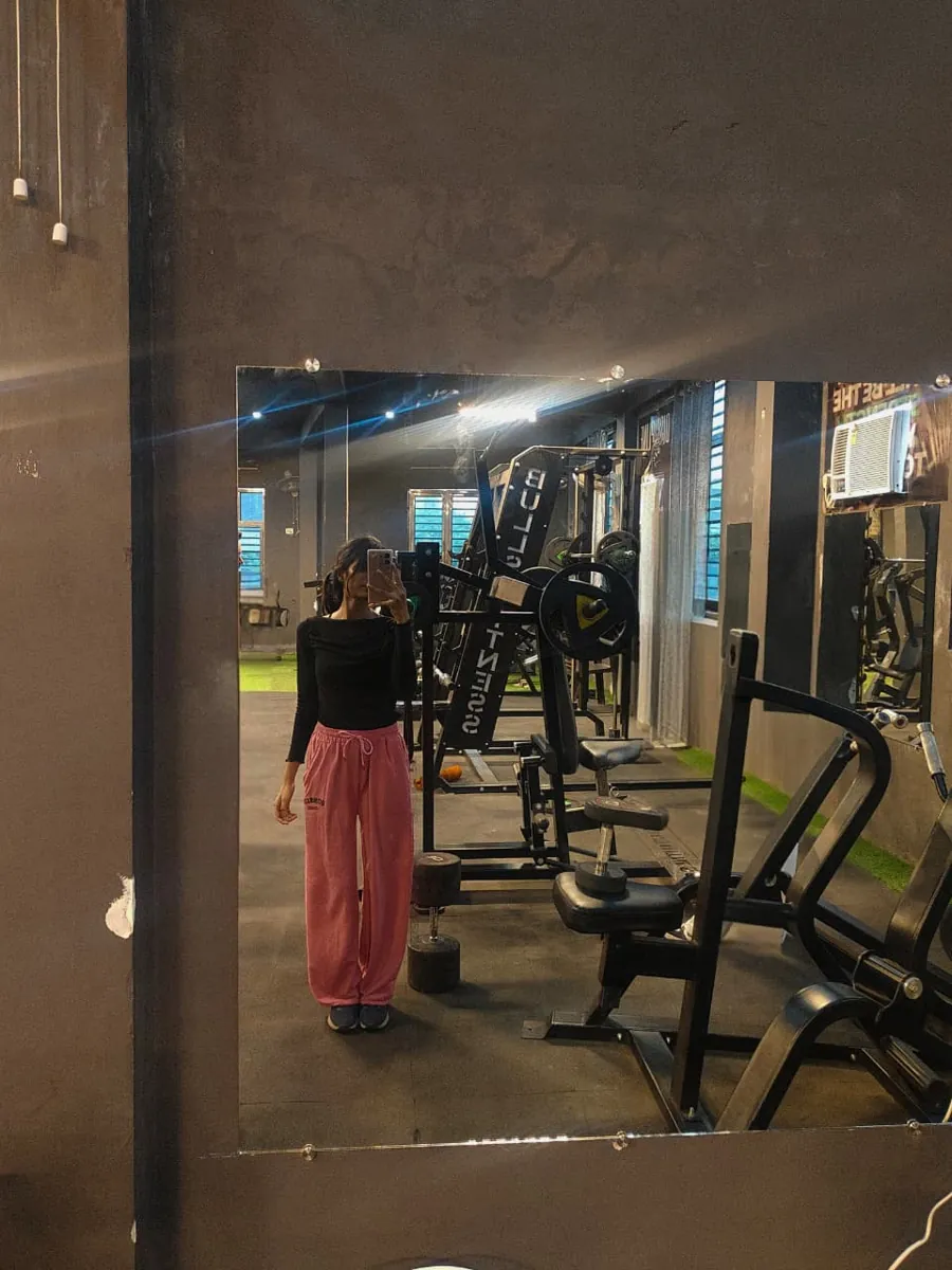 Khushi Gupta in the gym, mirror photo beside a plate-loaded machine
